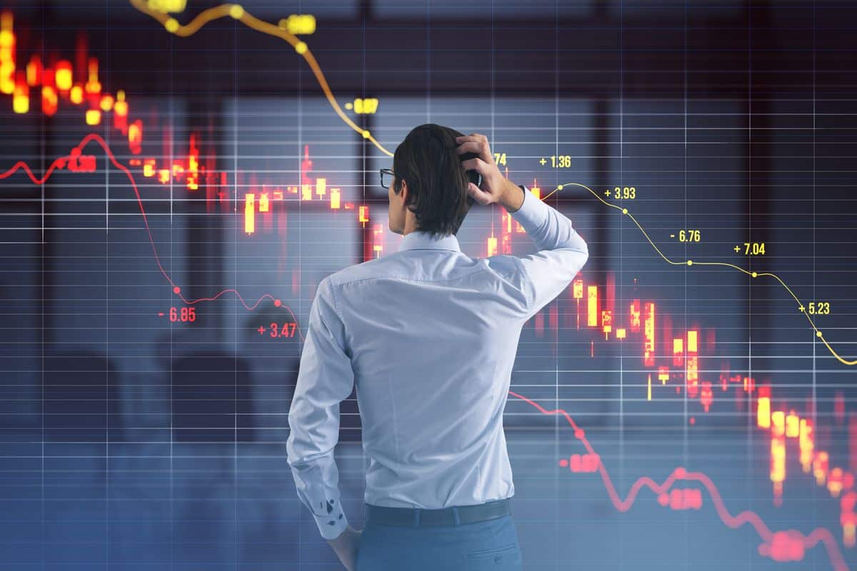 A worried investor looks at falling stock market charts on a digital screen, representing the volatility and risks associated with Index funds during market downturns.