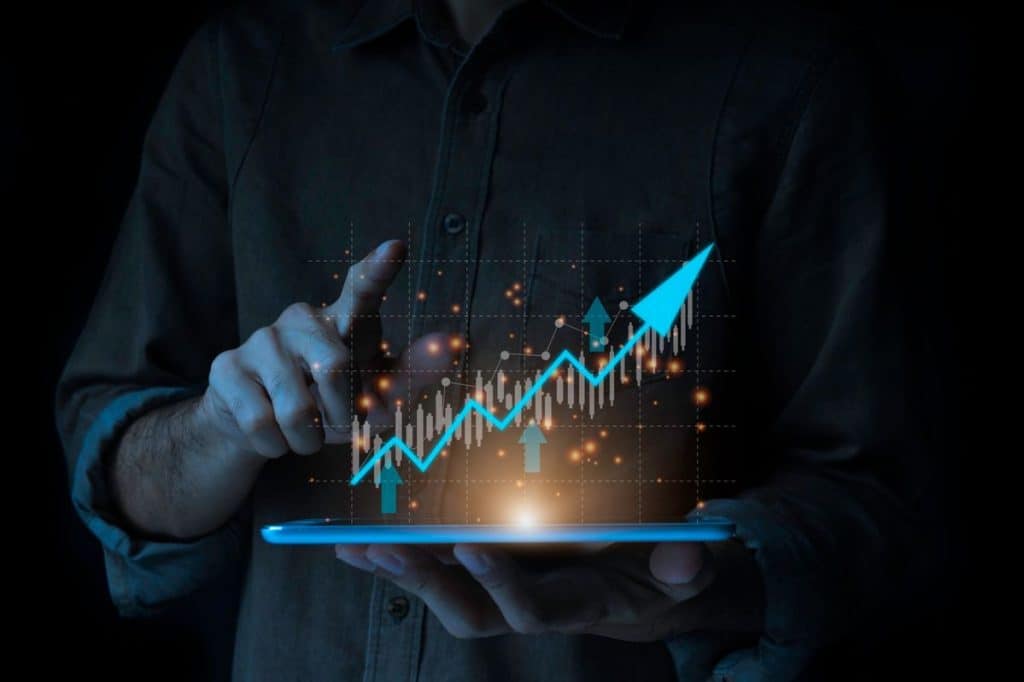 A person uses a tablet displaying a glowing upward financial chart, symbolizing the strategy to invest for the long term and achieve sustainable growth.