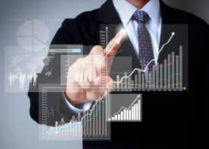 A businessman in a suit touches a virtual screen with multiple financial charts and graphs showing growth, symbolizing the power of smart investments and market analysis.