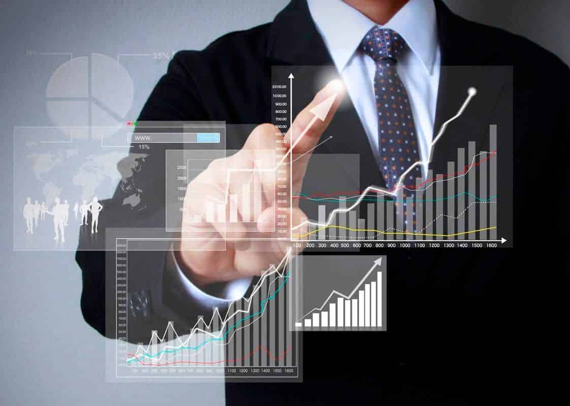A businessman in a suit touches a virtual screen with multiple financial charts and graphs showing growth, symbolizing the power of smart investments and market analysis.